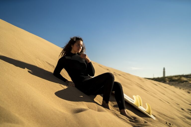 shallow-focus-shot-attractive-female-posing-sandy-hill-with-surfboard-side